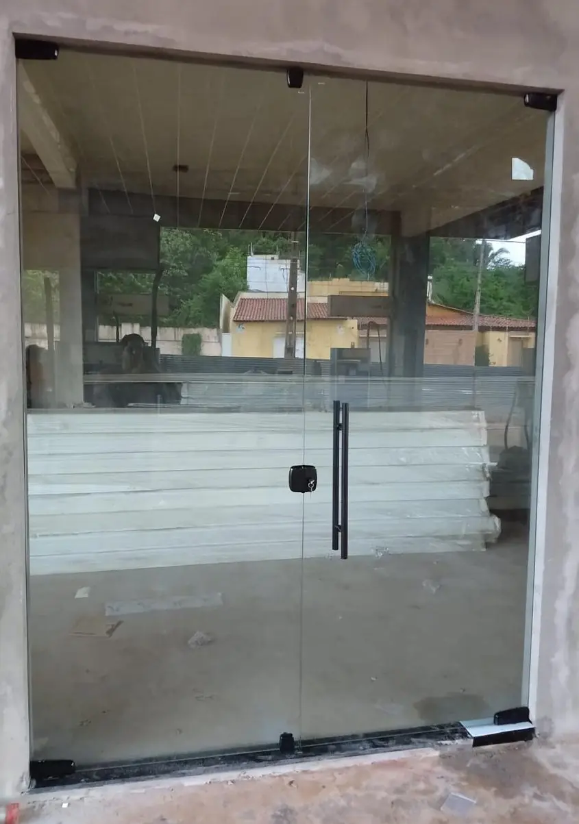 Porta pivotante de vidro em entrada, obra em fase de acabamento